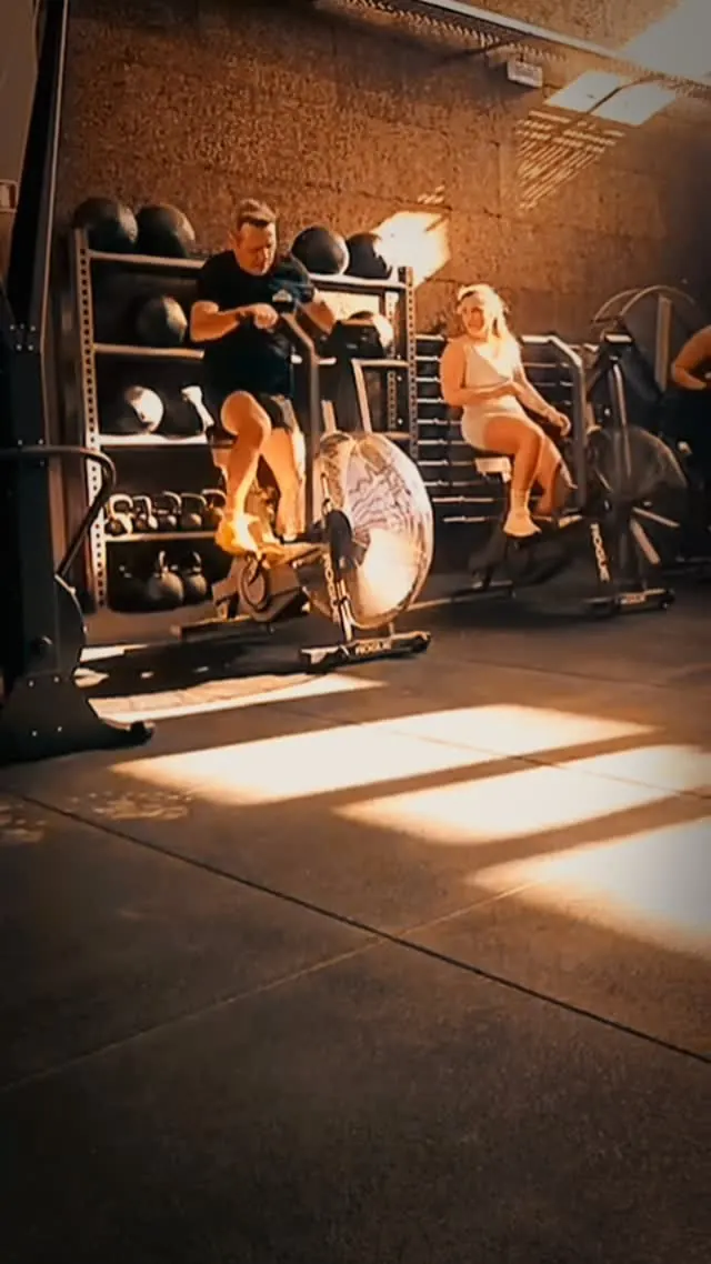 Dois atletas nas air bikes com luz de fim de tarde a entrar na box