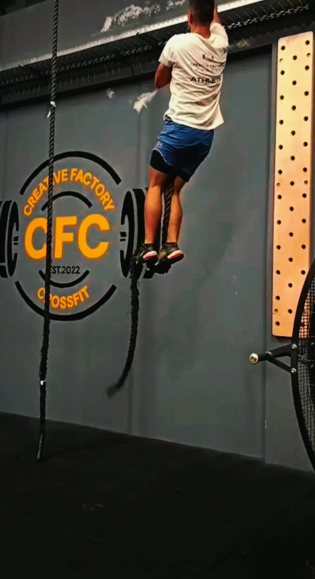 Atleta a subir a corda junto ao logótipo CFC pintado na parede da box